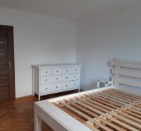 Ložnice s bílým nábytkem a podlahou s dřevěným dekorem v 2-pokojovém bytě.