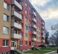 Bytový dům se schodištěm a balkóny, s parkováním před budovou, výhled na garsonku.