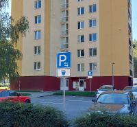 Bytový dům na Štvrti SNP v Trenčianských Teplicích s parkovištěm a zelení v popředí.