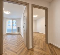 Interiér 3-pokojového bytu s podlahou s dřevěným dekorem a dostatkem denního světla.