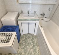 Koupelna s umyvadlem, vanou a pračkou ve 3-pokojovém bytě, obklady světlého odstínu.
