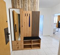 Vstupní chodba s dřevěným nábytkem a dlažbou v 2-pokojovém bytě.