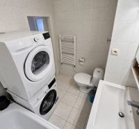 Koupelna se spotřebiči a sanitou v 2-pokojovém bytě, keramické obklady a dlažba.