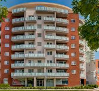 Výšková budova se zajímavými balkony u ulice Bosákova, blízko garáží ve městě.