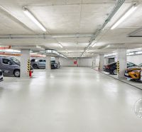 Podzemní garáže s vyznačenými parkovacími místy a zaparkovanými auty.