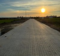 Zpevněná cesta na Vinohradech v Senici za soumraku s výhledem na město.