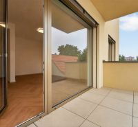 Prostorný balkon s výhledem a vstupem na podlahu s dřevěným dekorem v 3-pokojovém bytě.
