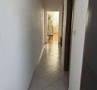 Úzká chodba s dlaždicovou podlahou vede k světlé místnosti ve 2-pokojovém bytě.