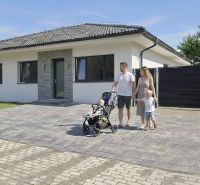 Rodinný dům v Hôrce nad Váhom s rodinou na dlážděné příjezdové cestě.