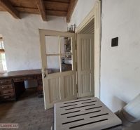 Interiér rodinného domu s masivním stolem a rustikálním dřevěným stropem.