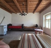Pokoj v rodinném domě s dřevěným stropem a kachlovými kamny.
