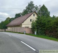 Rodinný dům ve Staškově s plechovou střechou, obklopený stromy a oplocením.