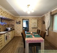 Interiér rodinného domu s podlahou s dřevěným dekorem, jídelním stolem a tapetami.