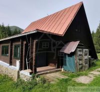 Chata v Rajecké Lesné s plechovou střechou a dřevěnými stěnami obklopená přírodou.