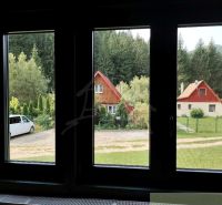Výhled na chaty v Rajecké Lesné, obklopené zelení a auty.