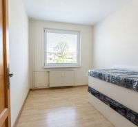 Světlý pokoj ve 3-pokojovém bytě s podlahou s dřevěným dekorem a postelí.