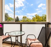 Zařízený balkon s kulatým stolem a dvěma židlemi ve 3-pokojovém bytě.