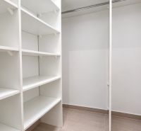 Úložný prostor s bílými regály v 2-pokojovém bytě.