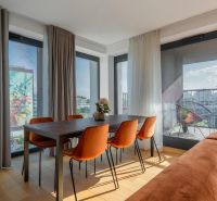 Jídelní kout s oranžovými židlemi, podlaha s dřevěným dekorem, výstup na balkon. Výstavba bytů.