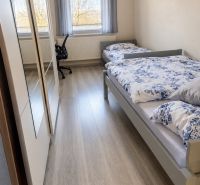 Pokoj s dvěma postelemi a podlahou s dřevěným dekorem v rodinném domě.