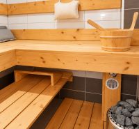 Sauna v rodinném domě s dřevěným obložením a kamny s kameny.