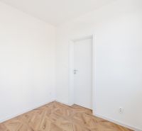 Pokoj se stěnami bílé barvy a podlahou s dřevěným dekorem, 2-pokojový byt.