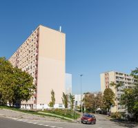 Bytové domy na Adámiho ulici v Bratislavě - Karlově Vsi obklopené zelení a cestou.