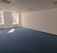 Prostorné kanceláře s modrým kobercem a stropními svítidly.