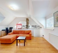 Světlý obývací pokoj s oranžovou sedačkou, pracovním koutem a podlahou s dřevěným dekorem.