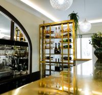 Elegantní vinotéka a bar v obchodních prostorách s moderním osvětlením a zlatými detaily.