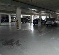 Podzemní garážové stání s parkovanými auty v 2-pokojovém bytě.