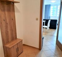 Předsíň v 2-pokojovém bytě s věšákovou stěnou a výhledem do obývacího pokoje s jídelnou.