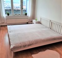 Světlá ložnice v 2pokojovém bytě s oknem a podlahou s dřevěným dekorem.