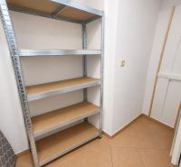 Úložný prostor v 2-pokojovém bytě s kovovým regálem a dlažbou.