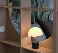 Designová lampa na poličce s tropickou tapetou v 1-pokojovém bytě.