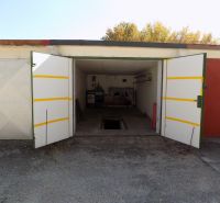 Otevřená garáž na Petőfiho řadě v Štúrovu s jámou a uskladněnými předměty.