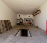 Garáže s montážní jámou a úložnými prostory s regály a dřevěnými plochami.