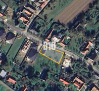 Letecký pohled na pozemek k bydlení v Moravském Lieskovém s viditelnou ulicí a budovami.