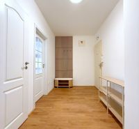 Chodba s bílými stěnami a podlahou s dřevěným dekorem v 2-pokojovém bytě.