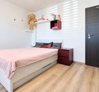 Ložnice v rodinném domě s růžovou postelí a podlahou s dřevěným dekorem.