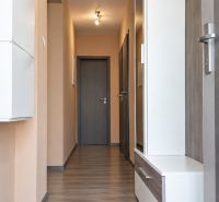 Chodba v rodinném domě s podlahou s dřevěným dekorem a světlými stěnami.