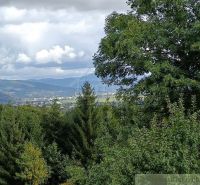 Výhled na přírodu z chaty ve Staškově s lesy a kopci v pozadí.