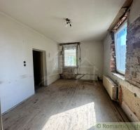 Ošuntělá místnost s podlahou s dřevěným dekorem čekající na renovaci v rodinném domě.