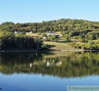 Pohled na rybník se stromy a kopci v Zahradách v Krupině.