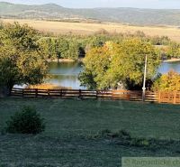 Slunečná scenérie v Zahradách Krupiny, s výhledem na jezero a kopce.