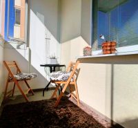 Balkon se dvěma skládacími židlemi a kobercem v 2-pokojovém bytě.