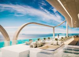 Luxusní bazénová terasa s lehátky a výhledem na oceán v rámci výstavby bytů.