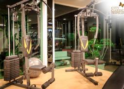 Fitness vybavení ve výstavbě bytů, zelené prvky, osvětlení a zrcadlové stěny.