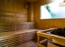 Dřevěná sauna s proskleným oknem a logem realitní kanceláře.