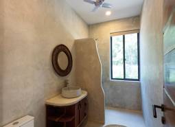 Koupelna s umyvadlem, kulatým kobercem a ventilátorem. Stavba domů.